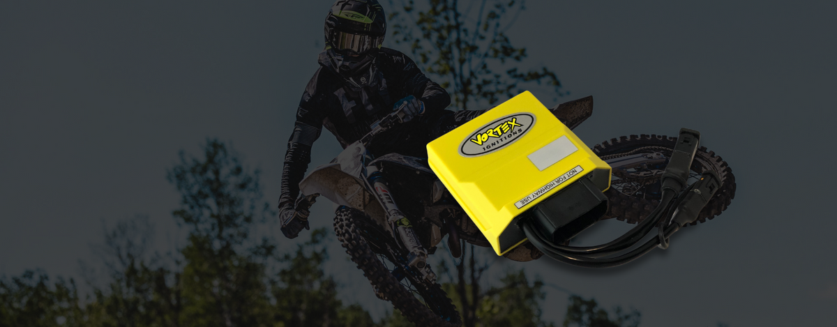 Module d'allumage Vortex Ignitions jaune devant un pilote de motocross en saut